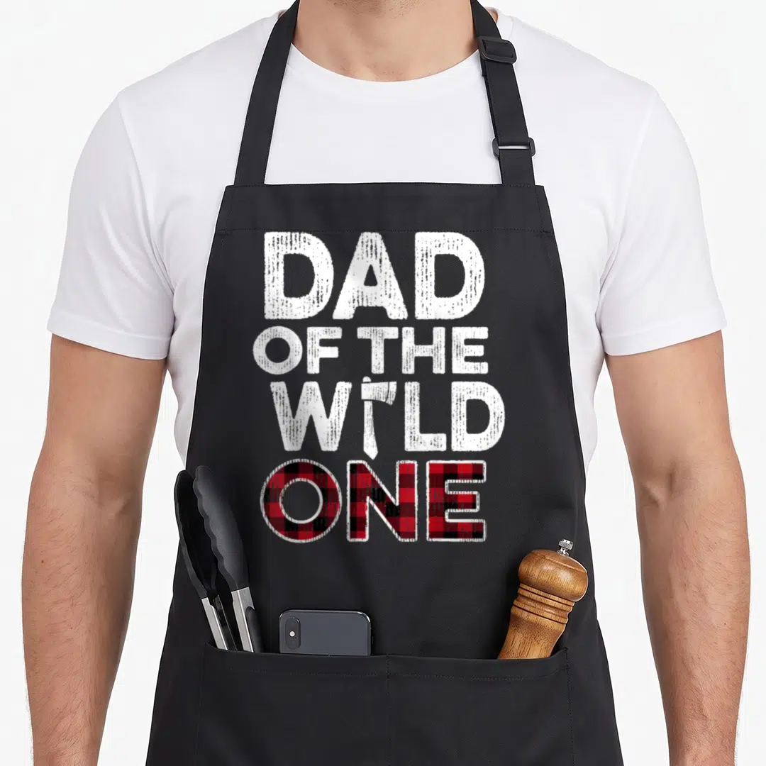 Lumberjack birthday apron - Dad of the Wild One text with axe and red black plaid ONE — shown on a black cotton canvas apron against a white background