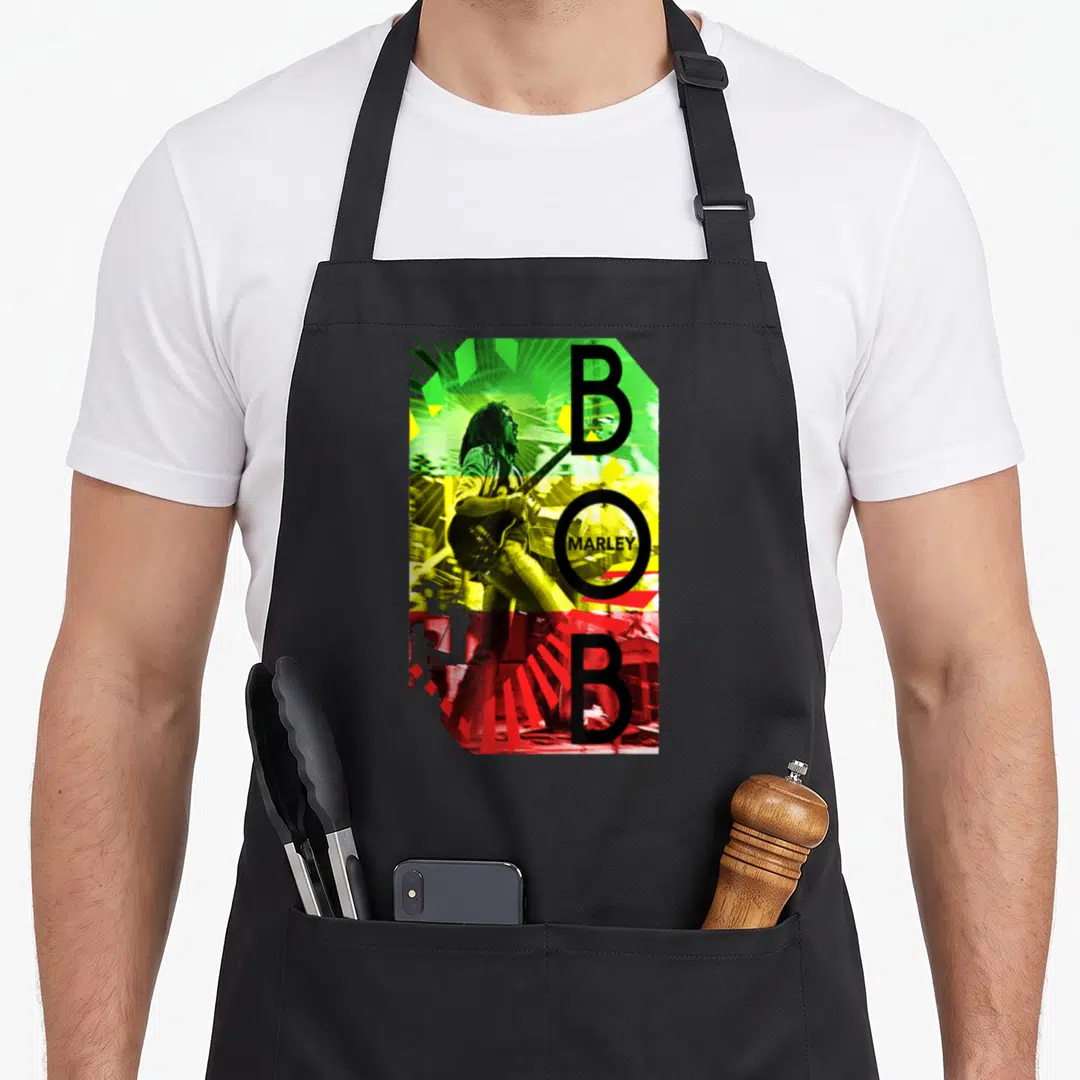Bob stripe apron - Retro Bob Marley guitar photo in green yellow red black with split BOB lettering — shown on a black cotton canvas apron against a white background