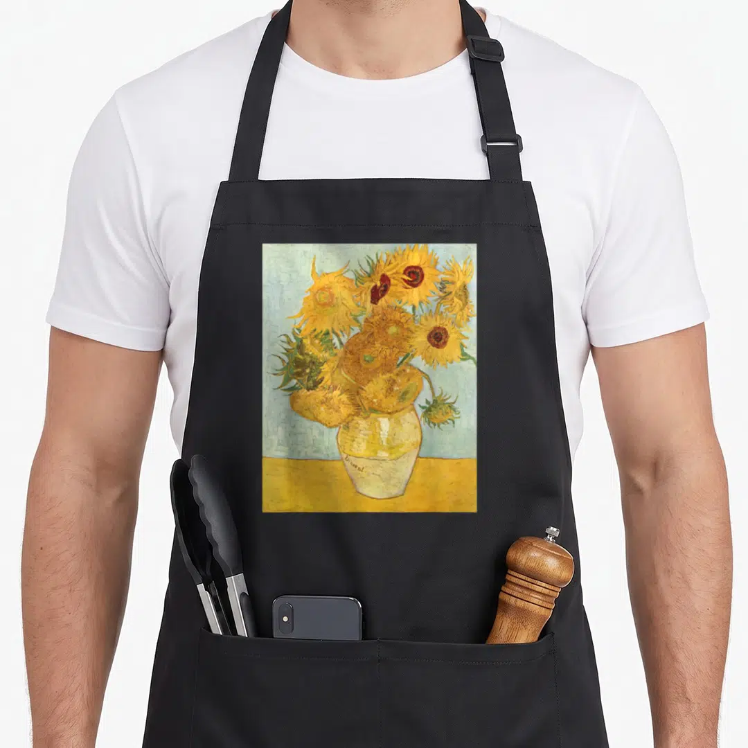 Sunflower van gogh apron - Bouquet of yellow sunflowers in a vase signed Vincent against a blue background — shown on a black cotton canvas apron against a white background