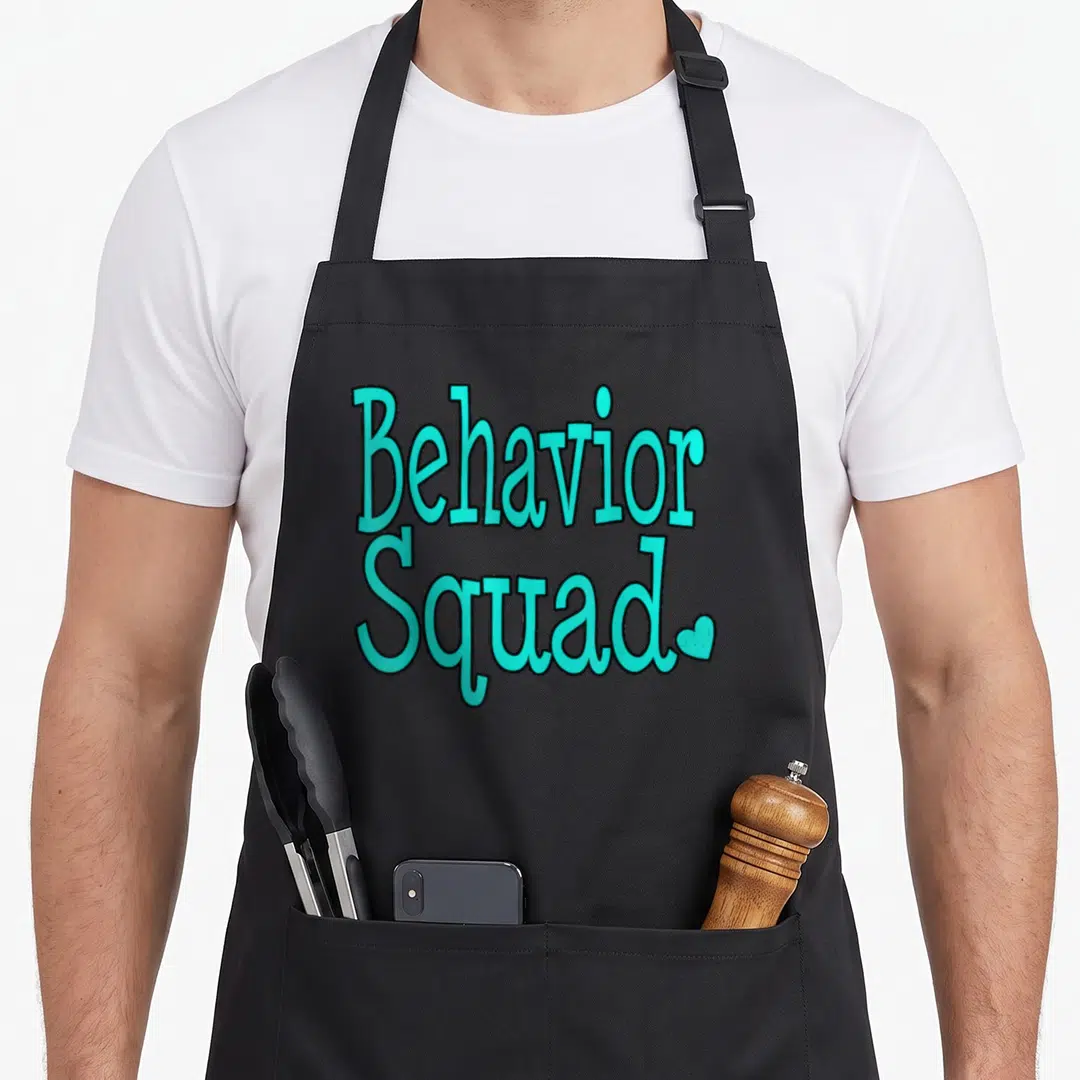 Behavior squad teacher apron - Cyan Behavior Squad text with small heart on black background — shown on a black cotton canvas apron against a white background