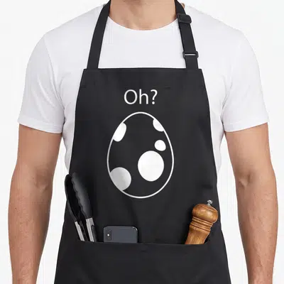 Hatching egg apron - White egg outline with internal spots and Oh? text above on black fabric — shown on a black cotton canvas apron against a white background