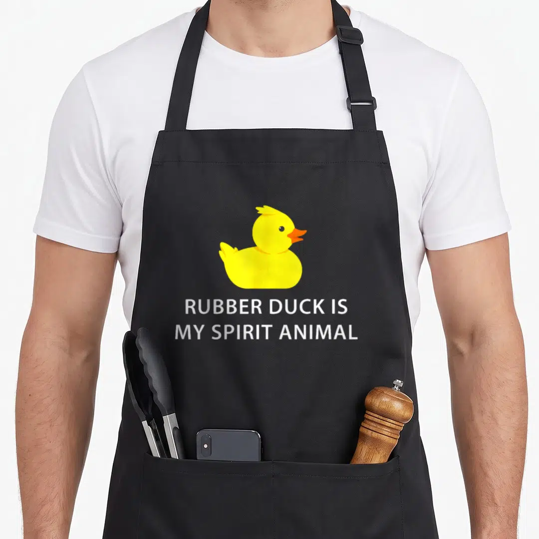 Animal rubber apron - Yellow rubber duck above white text reading RUBBER DUCK IS, MY SPIRIT ANIMAL — shown on a black cotton canvas apron against a white background