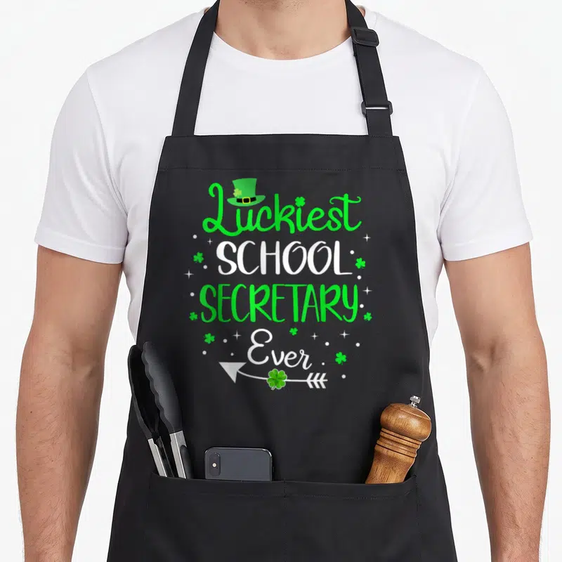 School st patrick day aprons - Luckiest School Secretary Ever text with green leprechaun hat and shamrock arrow — shown on a black cotton canvas apron against a white background