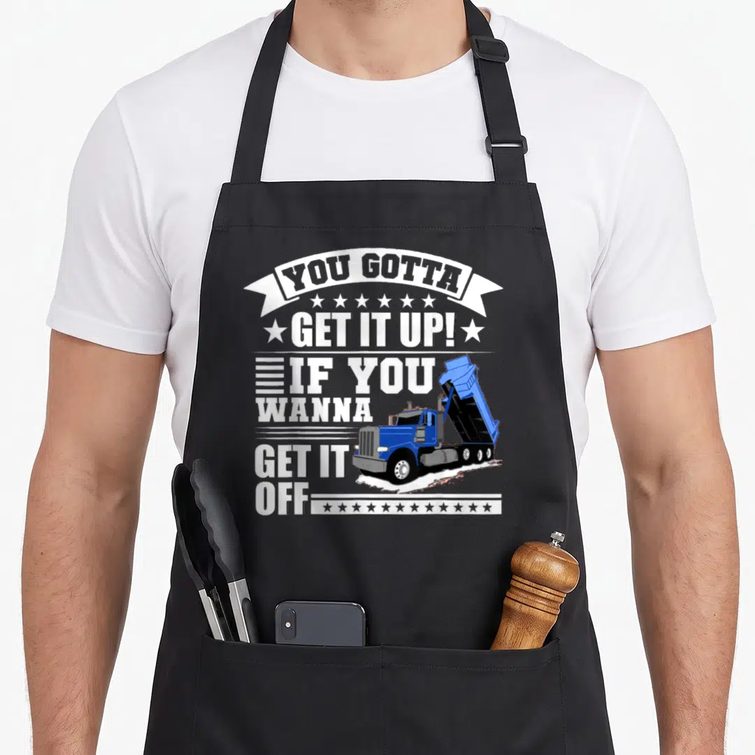 Funny dump truck apron - Blue dump truck graphic with You Gotta Get It Up text and stars — shown on a black cotton canvas apron against a white background