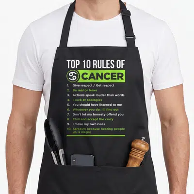 Feature zodiac aprons - Top 10 Rules of Cancer text list in lime green and white typography — shown on a black cotton canvas apron against a white background