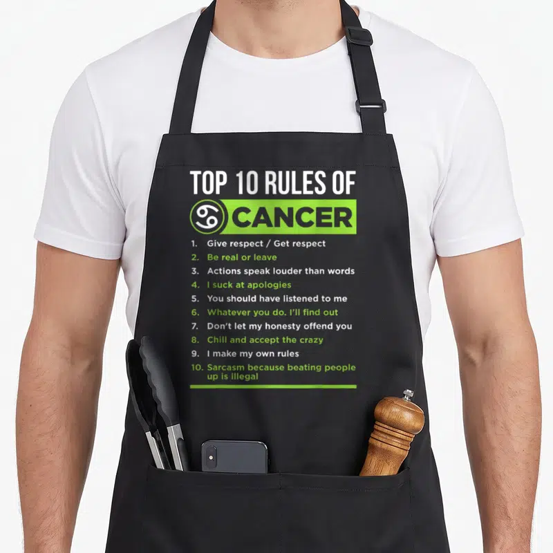 Feature zodiac aprons - Top 10 Rules of Cancer text list in lime green and white typography — shown on a black cotton canvas apron against a white background