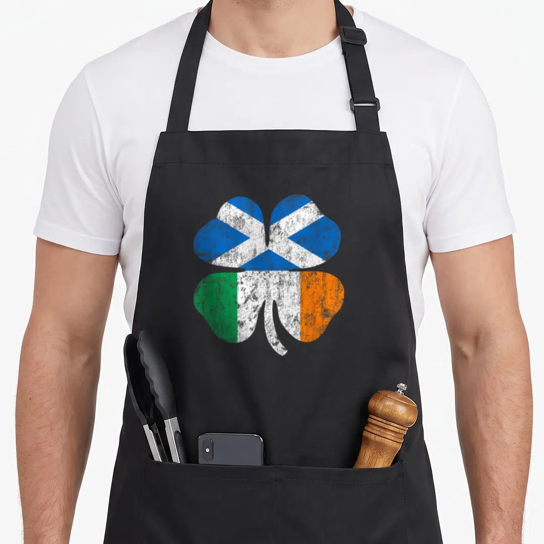 Scottish ireland apron - Distressed shamrock with Scottish saltire and Irish tricolor flag fills inside — shown on a black cotton canvas apron against a white background