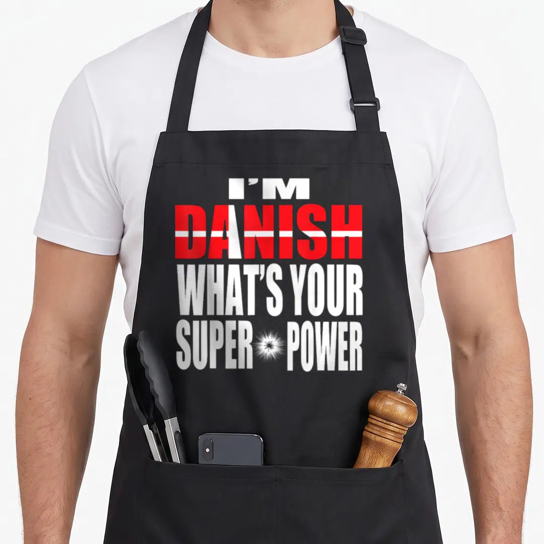 Culture danish girl apron - Stacked text I'M DANISH WHAT'S YOUR SUPER POWER with red flag pattern fill and white — shown on a black cotton canvas apron against a white background