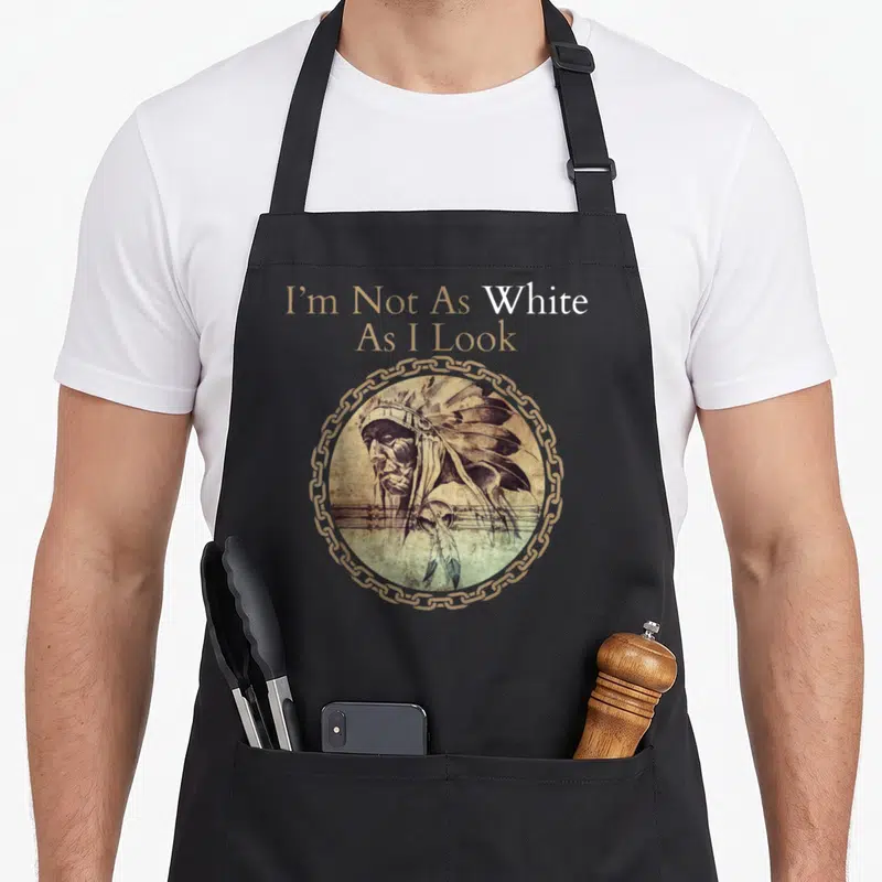 Funny heritage native american aprons - Stacked text I'm Not As White As I Look above circular portrait of man — shown on a black cotton canvas apron against a white background