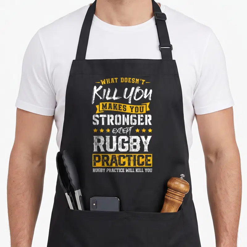 Practice rugby player apron - Distressed white and yellow text quote about rugby practice killing you with stars — shown on a black cotton canvas apron against a white background