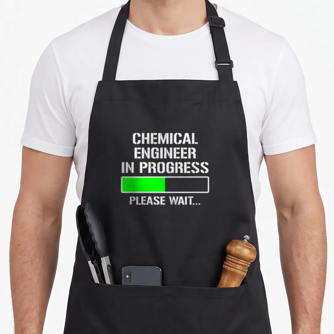 Engineer chemical apron - Stacked white text reading CHEMICAL ENGINEER IN PROGRESS above a green loading bar — shown on a black cotton canvas apron against a white background