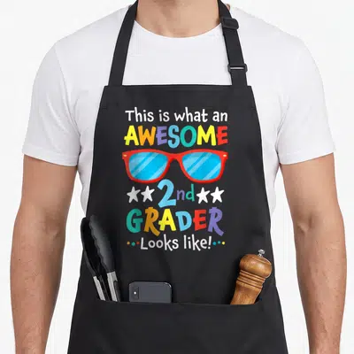 Grader 2nd apron - Colorful text This is what an AWESOME 2nd GRADER Looks like surrounding red sunglasses with blue — shown on a black cotton canvas apron against a white background