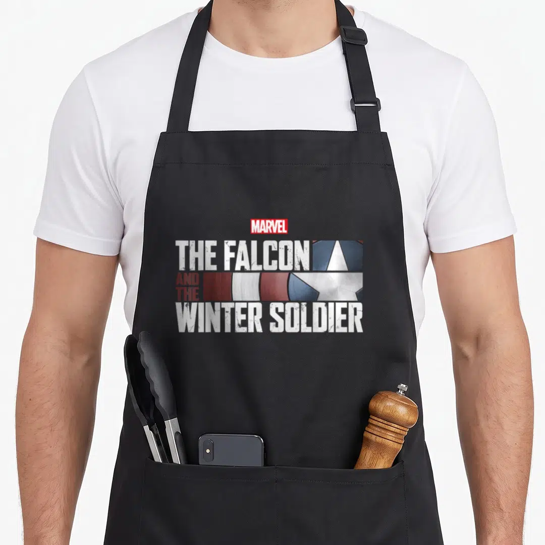 Falcon winter apron - The Falcon And The Winter Soldier shield logo with MARVEL text in white, red, silver, and blue — shown on a black cotton canvas apron against a white background