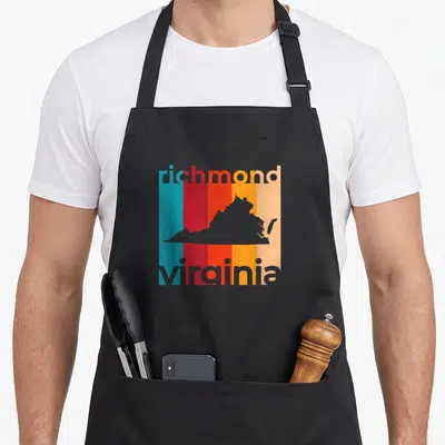 Repeat richmond apron - Grey Virginia map silhouette over five vertical stripes in teal red orange yellow and peach — shown on a black cotton canvas apron against a white background