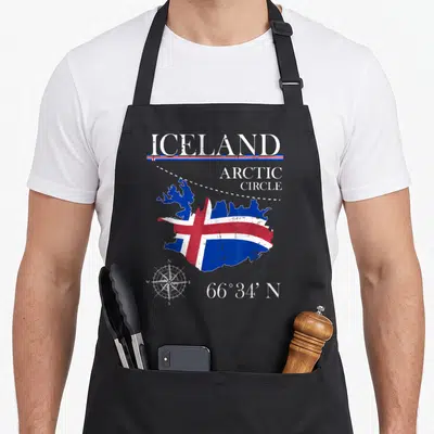 Iceland icelandic apron - Distressed Iceland map filled with flag, Arctic Circle text, compass, and 66 degrees 34 — shown on a black cotton canvas apron against a white background