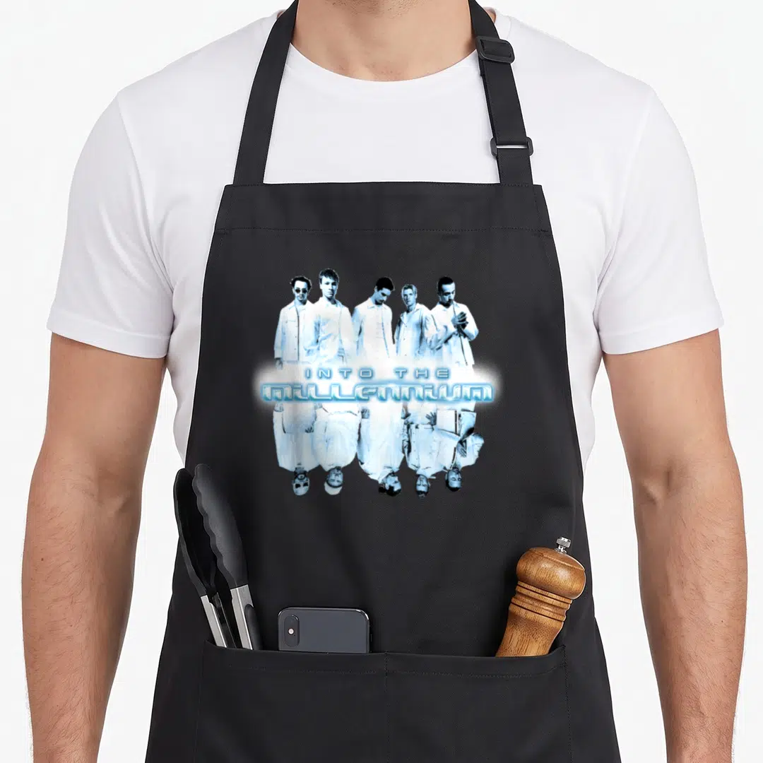 Las backstreet boys apron - Five men in white outfits with INTO THE MILLENNIUM text and mirrored reflection in blue — shown on a black cotton canvas apron against a white background