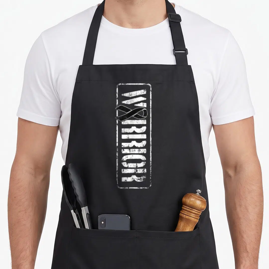 Melanoma military apron - Vertical WARRIOR text in white distressed stencil inside a rectangle with a black awareness — shown on a black cotton canvas apron against a white background