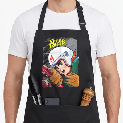Manga racer girl apron - Speed Racer character in white M helmet holding red steering wheel with yellow text — shown on a black cotton canvas apron against a white background
