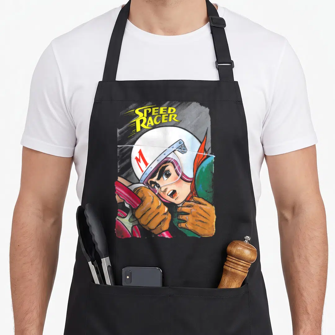 Manga racer girl apron - Speed Racer character in white M helmet holding red steering wheel with yellow text — shown on a black cotton canvas apron against a white background