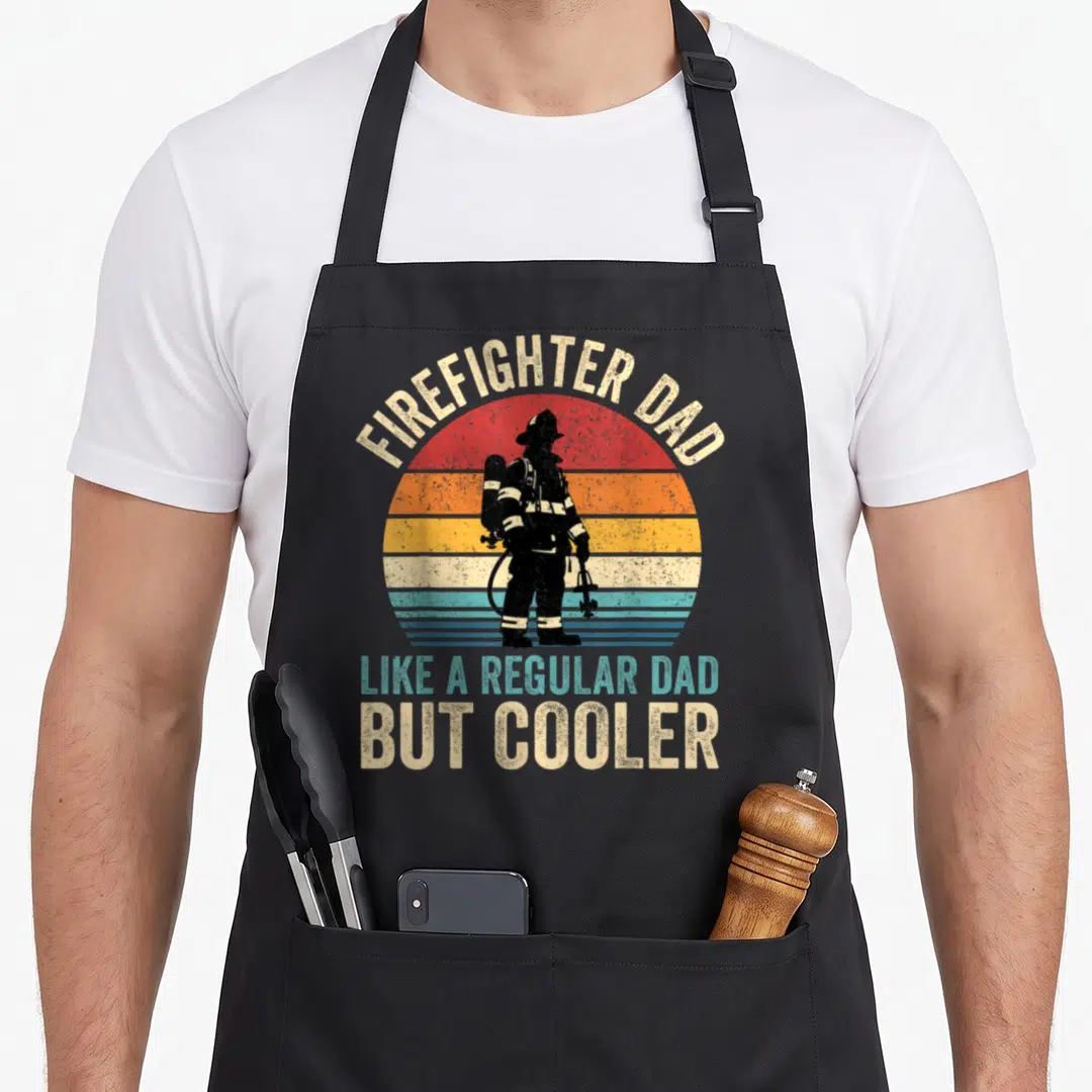 But firefighter aprons - Retro firefighter dad silhouette against striped sun with arched text reading Like a regular — shown on a black cotton canvas apron against a white background