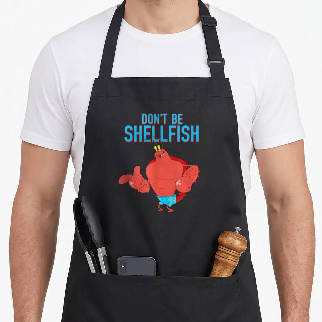 Larry lobster apron - Muscular red lobster in blue swim trunks under stacked text reading Don't Be Shellfish — shown on a black cotton canvas apron against a white background
