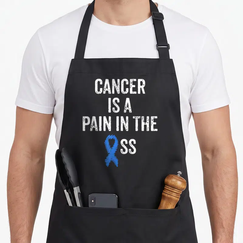 Colonoscopy colon cancer awareness apron - White distressed text reading CANCER IS A PAIN IN THE SS with a blue — shown on a black cotton canvas apron against a white background