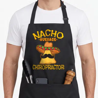 Chiropractor mexican apron - Nacho Average Chiropractor text above yellow chip wearing sombrero and mustache — shown on a black cotton canvas apron against a white background