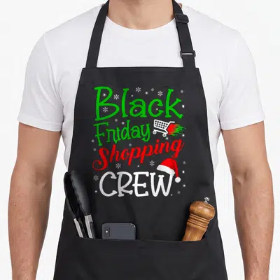 Crew black friday apron - Stacked text Black Friday Shopping CREW with flaming cart and Santa hat snowflakes — shown on a black cotton canvas apron against a white background