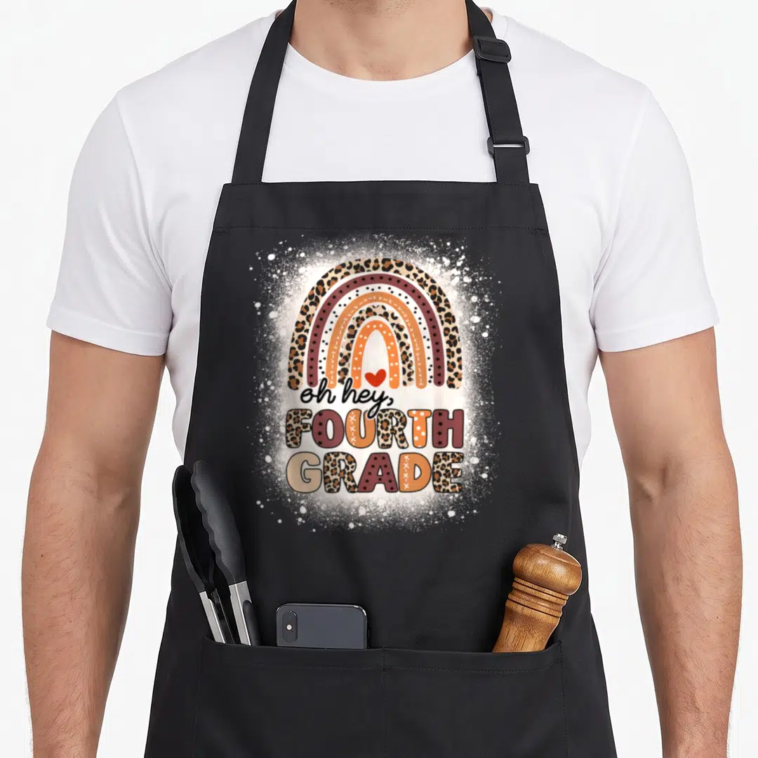 Hey rainbow apron - Retro leopard print rainbow with oh hey fourth grade text and red heart — shown on a black cotton canvas apron against a white background
