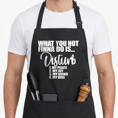 Finna grind apron - White stacked typography reading disturb my peace joy grind vibe on black apron — shown on a black cotton canvas apron against a white background