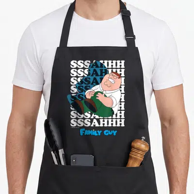 Knee griffin apron - Peter Griffin holding knee over SSSAHHH text and Family Guy logo — shown on a black cotton canvas apron against a white background