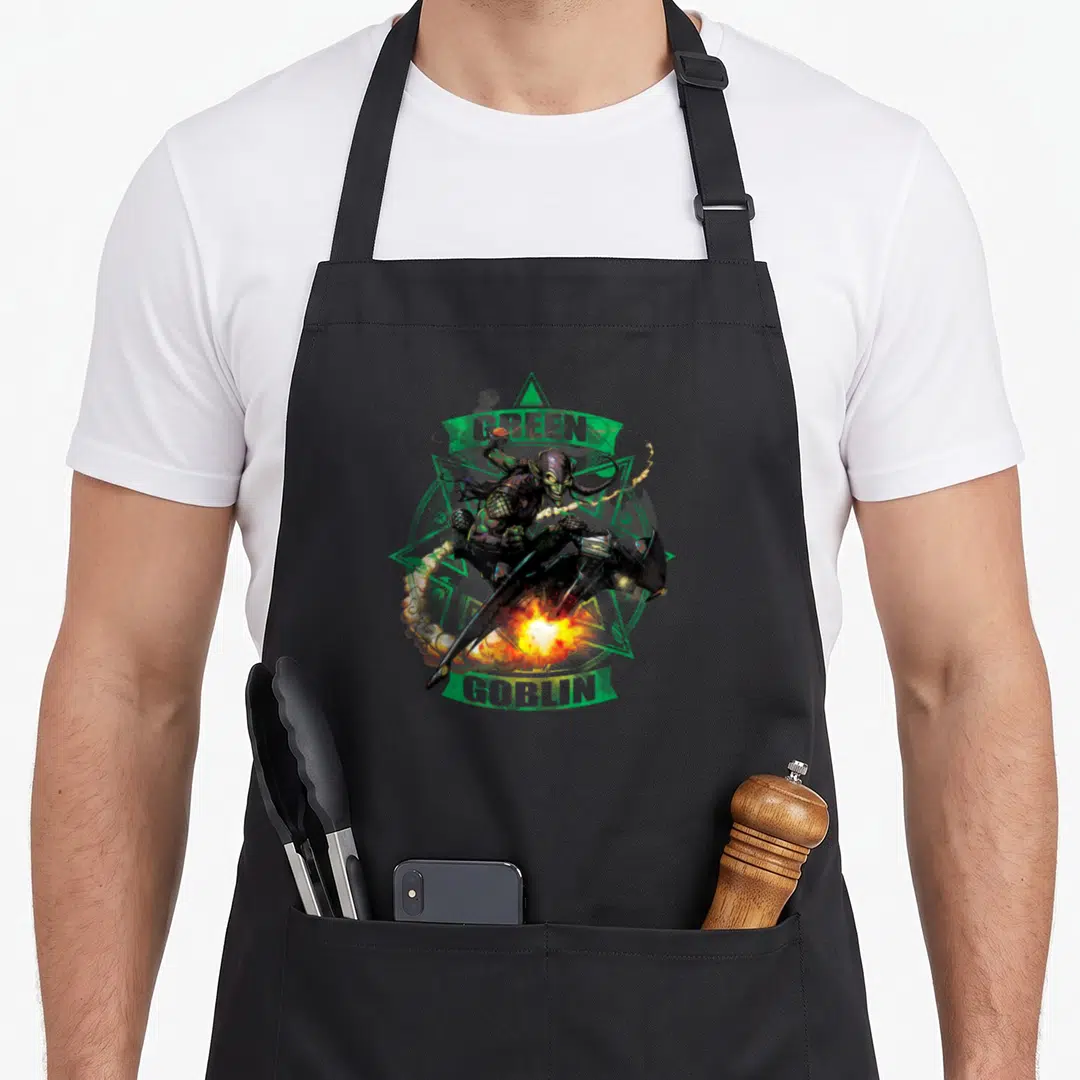 Goblin pumpkin apron - Realistic Green Goblin on glider with banners reading GREEN and GOBLIN over green triangle — shown on a black cotton canvas apron against a white background