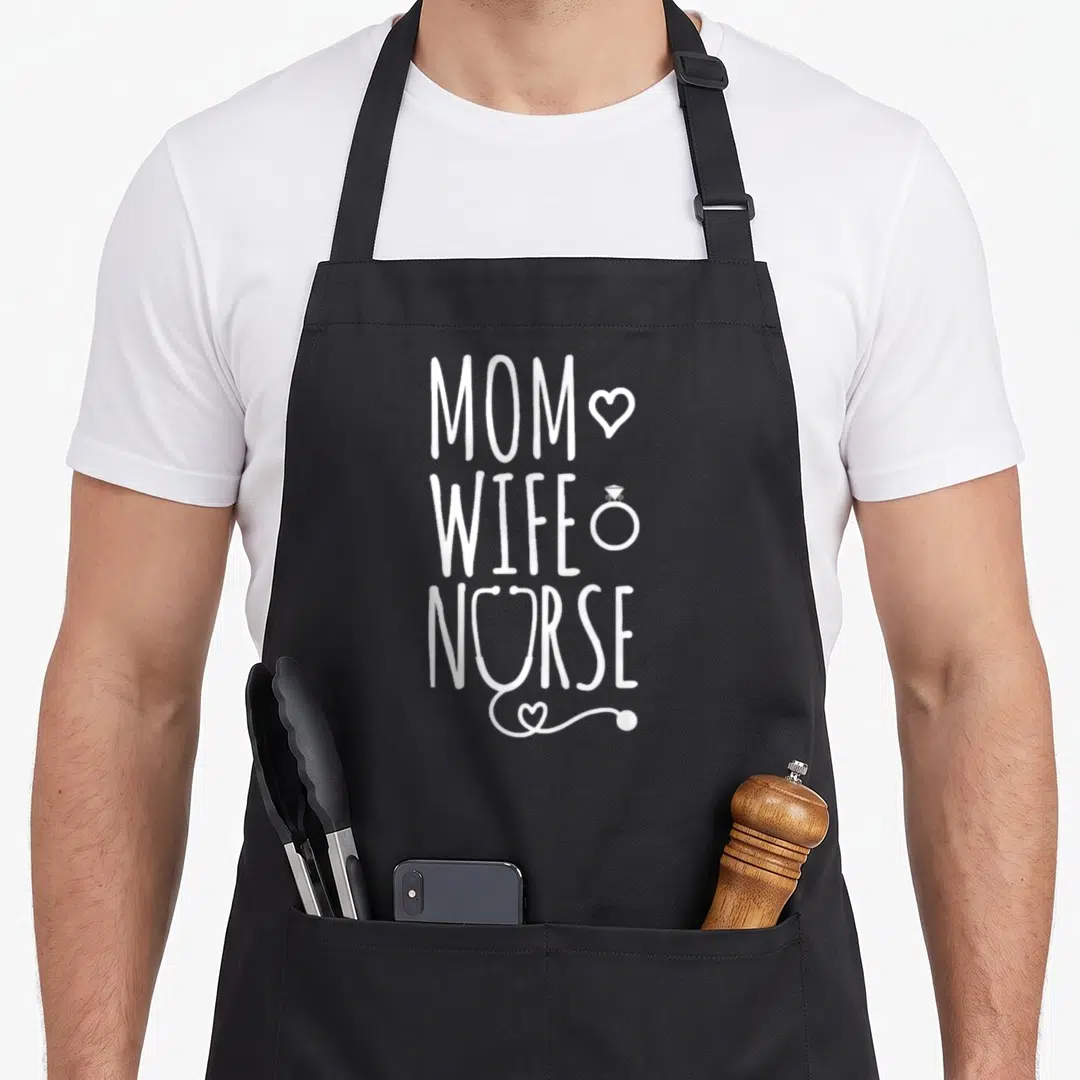 Funny wife white nurse apron - Vertical white MOM WIFE NURSE text with heart ring and stethoscope heart icon — shown on a black cotton canvas apron against a white background