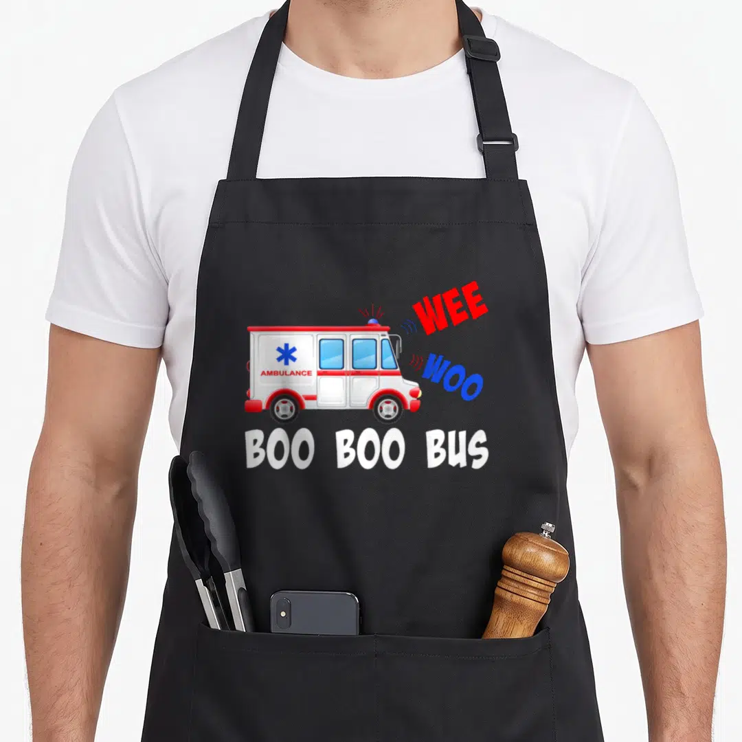 Wee medic apron - Cartoon ambulance with WEE WOO and BOO BOO BUS text in red blue and white — shown on a black cotton canvas apron against a white background