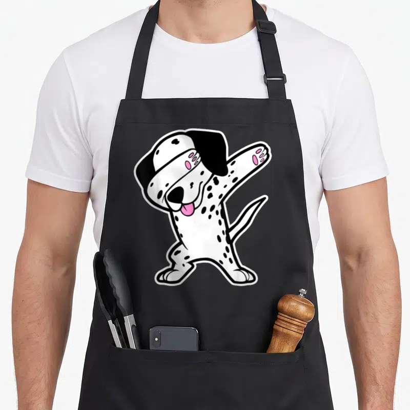 Dalmation dog apron - Cartoon dalmatian standing and dabbing with pink tongue and pads — shown on a black cotton canvas apron against a white background