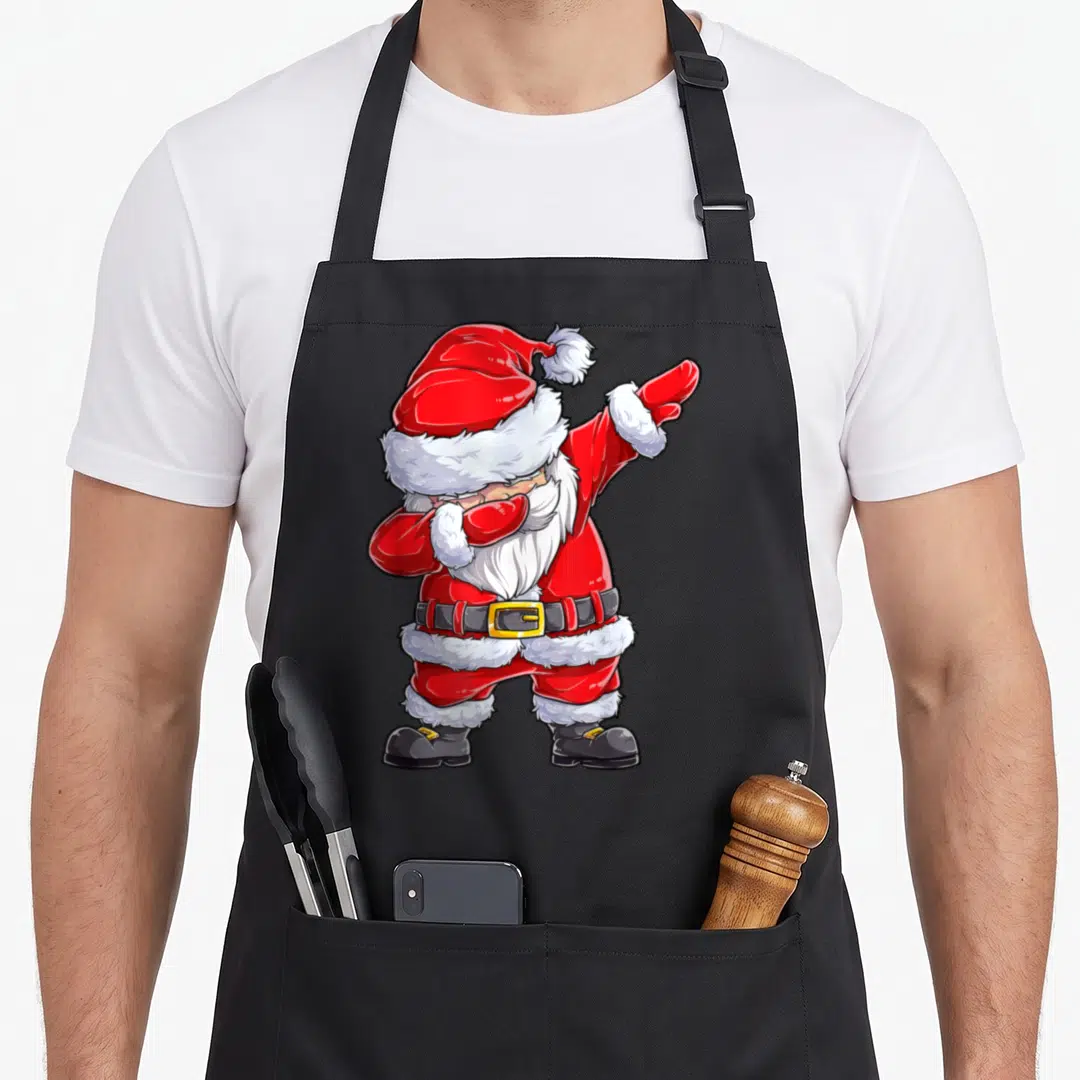 Christmas santa claus apron - Cartoon Santa Claus in red suit performing a dab dance pose with white beard and black — shown on a black cotton canvas apron against a white background