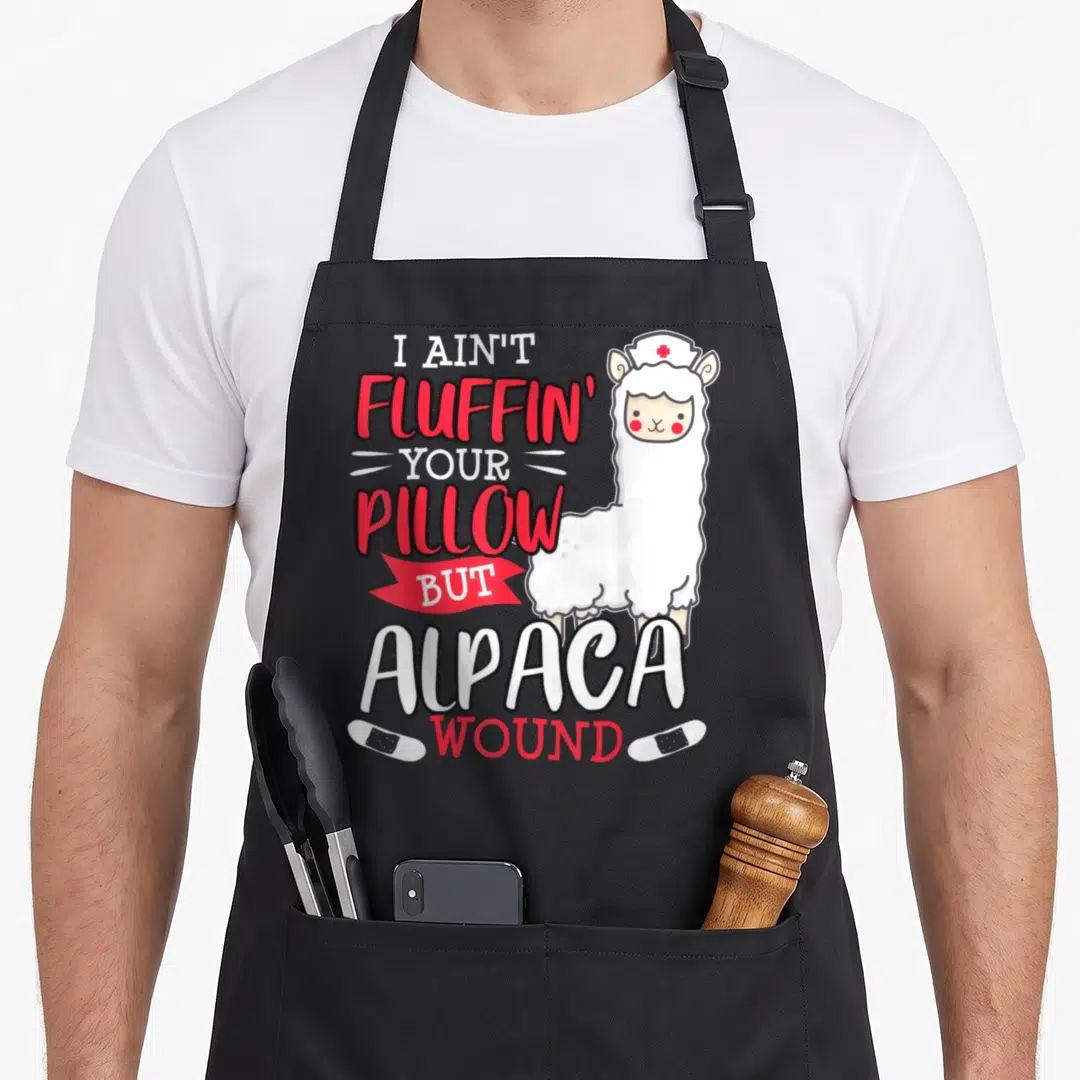 Wound nursing student apron - Cartoon alpaca nurse with I AIN'T FLUFFIN YOUR PILLOW BUT ALPACA WOUND text and bandages — shown on a black cotton canvas apron against a white background