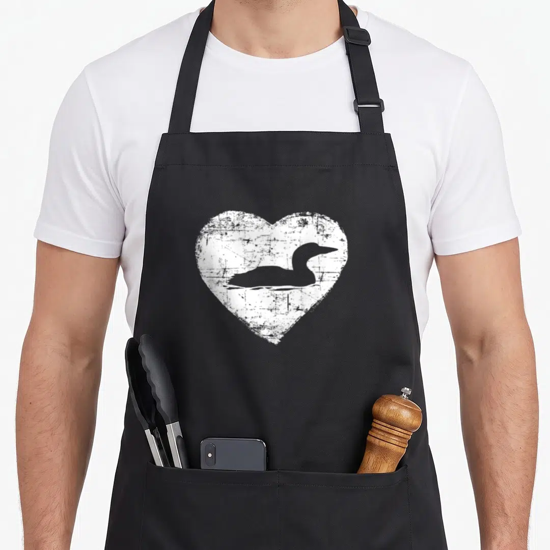 Loon lake apron - Grey duck silhouette inside a white distressed heart on an apron front panel — shown on a black cotton canvas apron against a white background