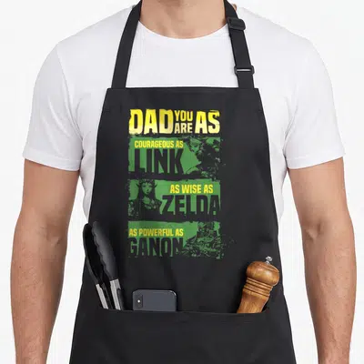 Relate game aprons - DAD YOU ARE AS Link Zelda Ganon distressed text over green portrait blocks — shown on a black cotton canvas apron against a white background