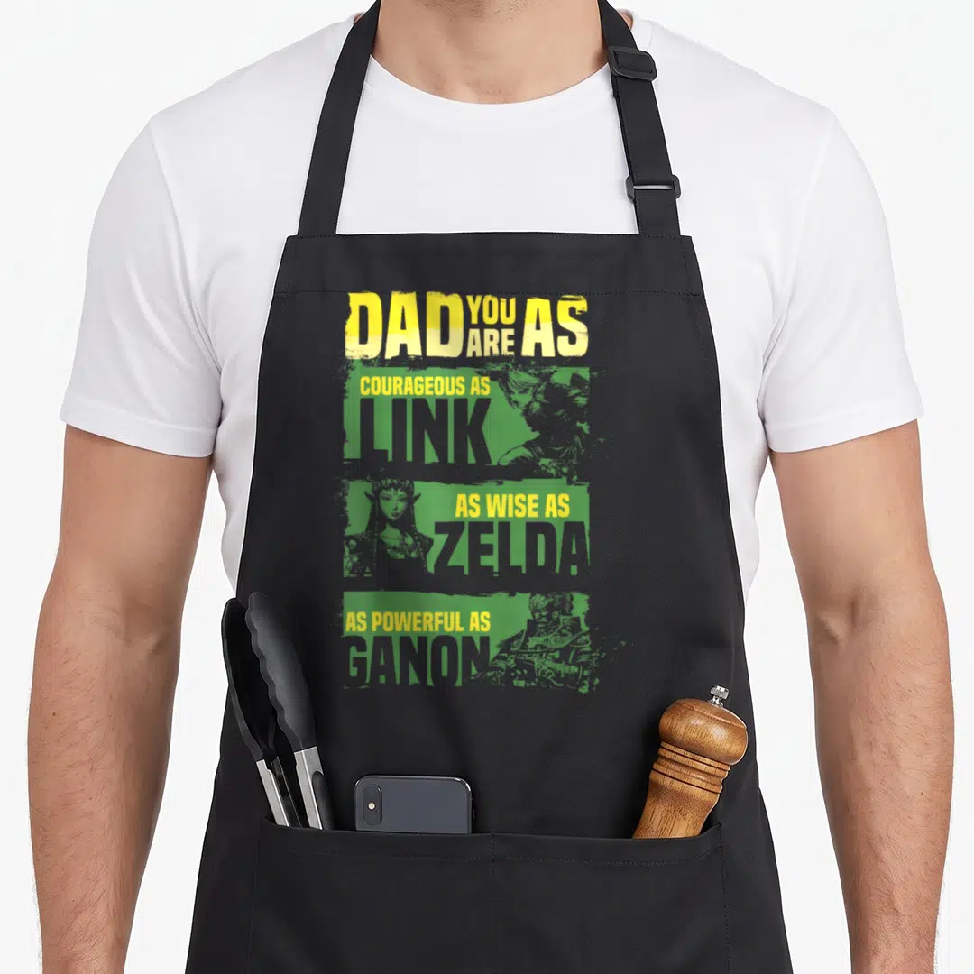 Relate game aprons - DAD YOU ARE AS Link Zelda Ganon distressed text over green portrait blocks — shown on a black cotton canvas apron against a white background