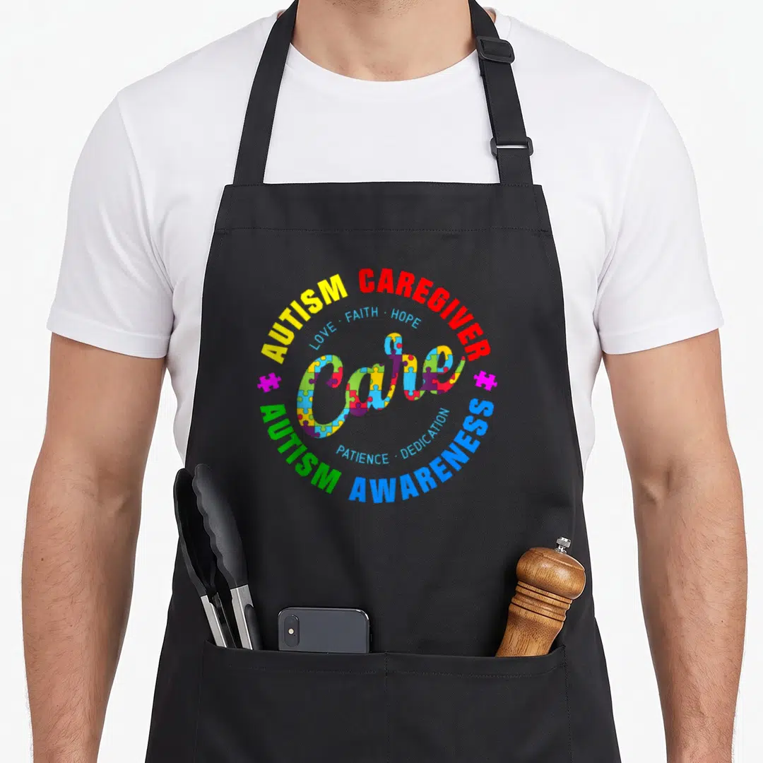 Autism caregiver apron - Central word Care filled with puzzle pieces surrounded by concentric circles of red yellow — shown on a black cotton canvas apron against a white background