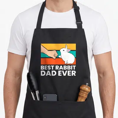 Funny rabbit apron - White rabbit and human fist bump over orange teal and red stripes with bold text — shown on a black cotton canvas apron against a white background