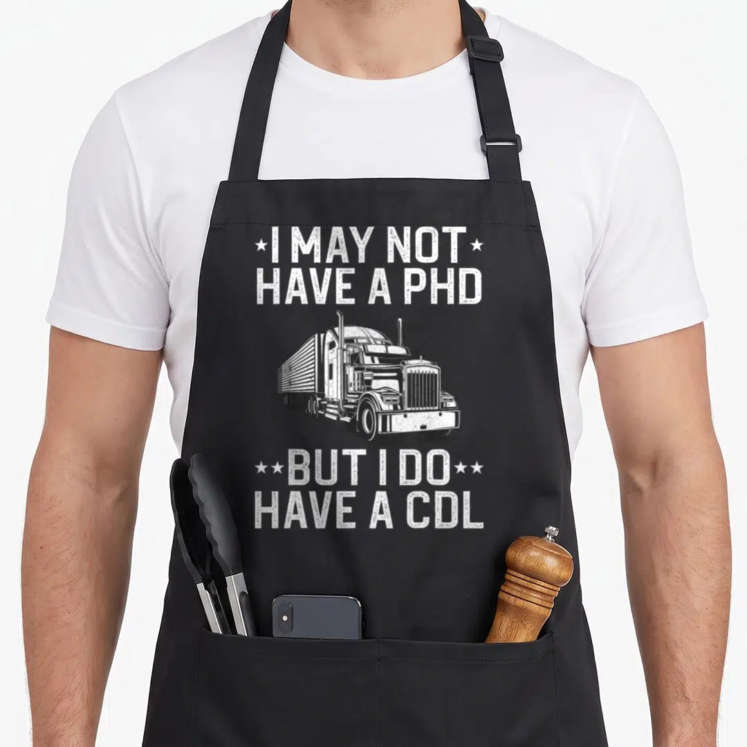 Trucker cdl truck apron - Distressed semi-truck illustration with white text I may not have a PhD but I do have a CDL — shown on a black cotton canvas apron against a white background