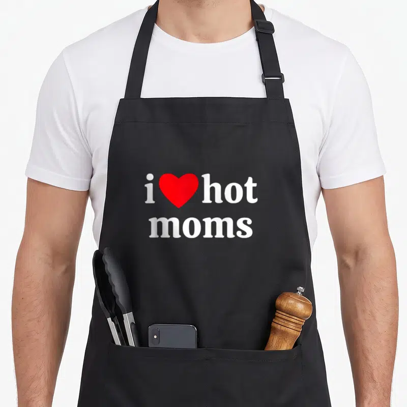 Funny hot apron - White text reading i heart hot moms with a red heart symbol replacing the word love — shown on a black cotton canvas apron against a white background
