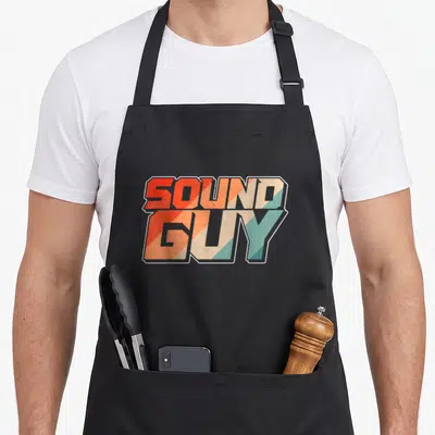 Audio sound engineer apron - SOUND GUY stacked typography in orange beige and teal retro style — shown on a black cotton canvas apron against a white background