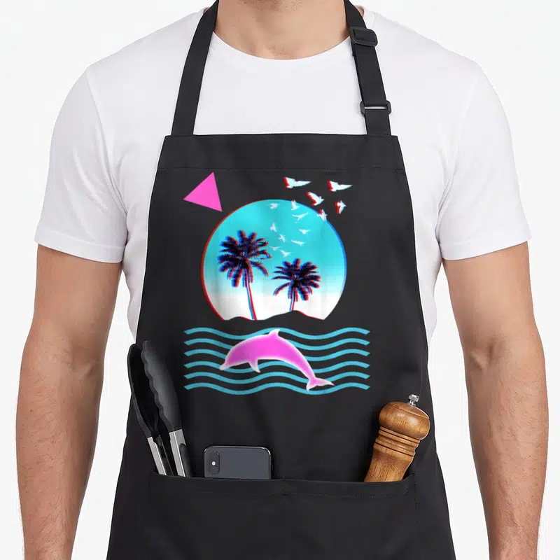 Vaporwave tree apron - Pink dolphin jumping over blue waves below circle with two palm trees and flying white birds — shown on a black cotton canvas apron against a white background