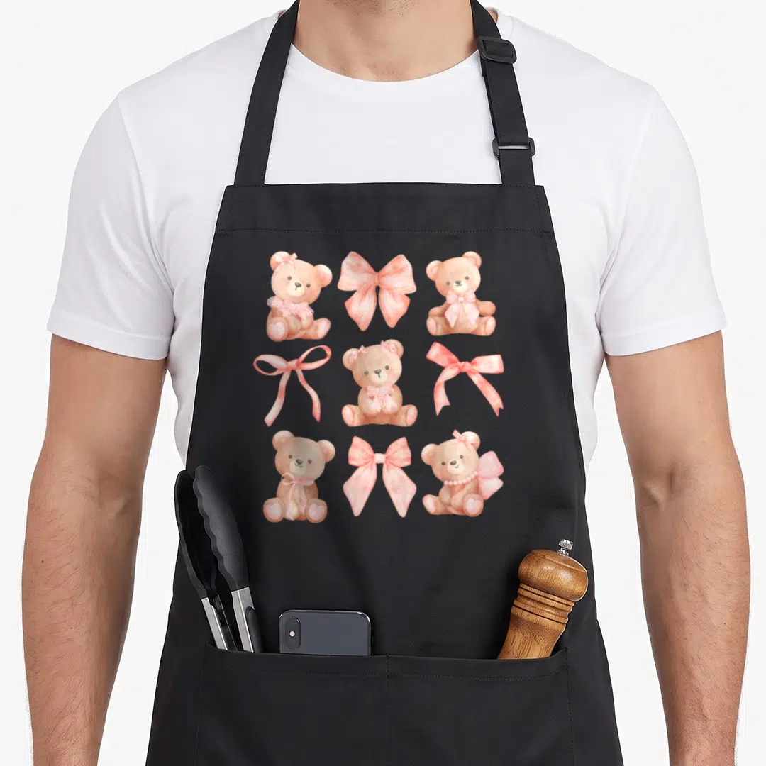 Coquette teddy bear apron - Brown teddy bears and pink bows in a watercolor 3x3 grid pattern — shown on a black cotton canvas apron against a white background