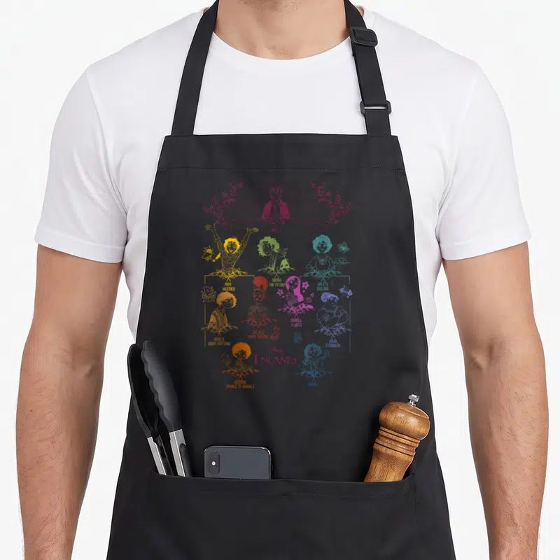 Portrait tree apron - Encanto family tree line art with character names and powers in maroon yellow green teal orange — shown on a black cotton canvas apron against a white background