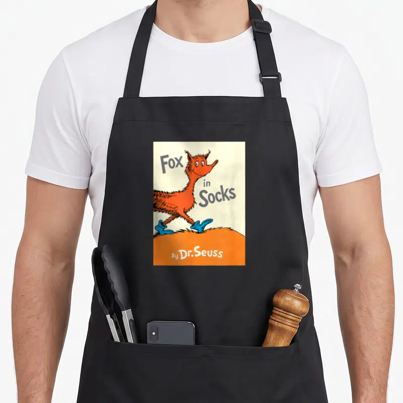 Sock fox print apron - Cartoon fox in blue socks with grey Fox in Socks text on orange ground — shown on a black cotton canvas apron against a white background