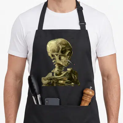 Vincent skeleton apron - Realistic painting of a skeleton head and shoulders smoking a cigarette in brown and black — shown on a black cotton canvas apron against a white background